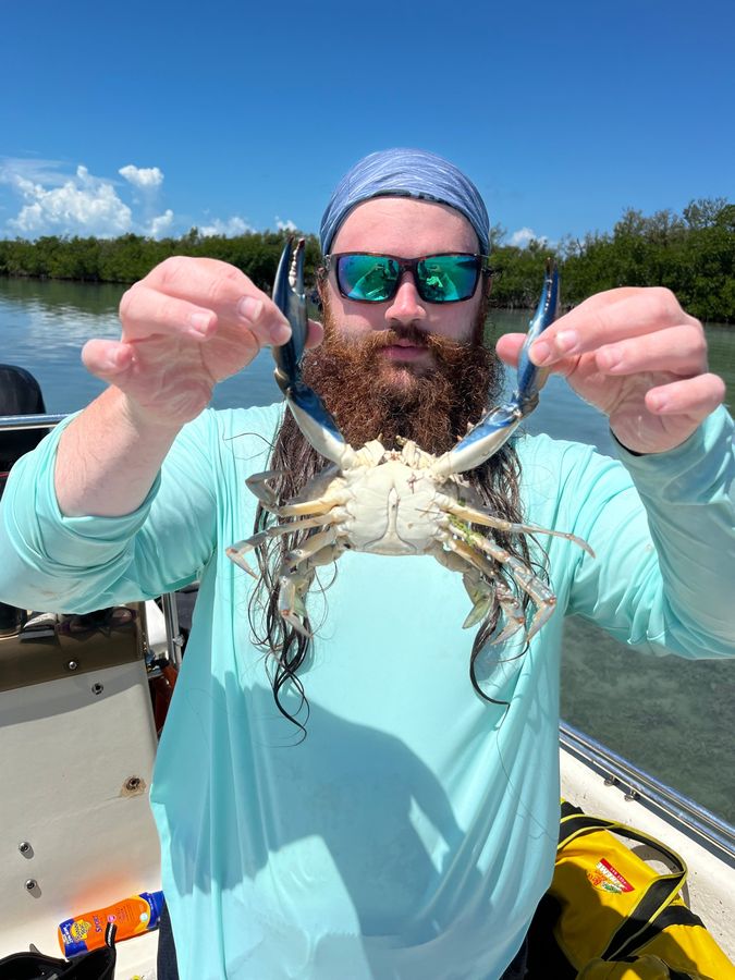 Holding up a blue crab by its claws on a boat