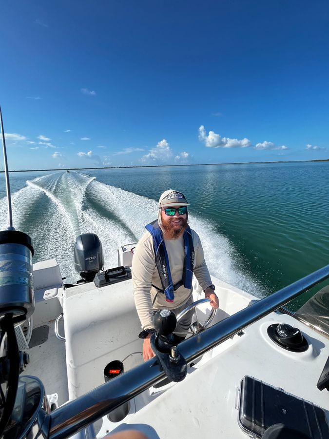 Mack driving a boat with a long white wake behind