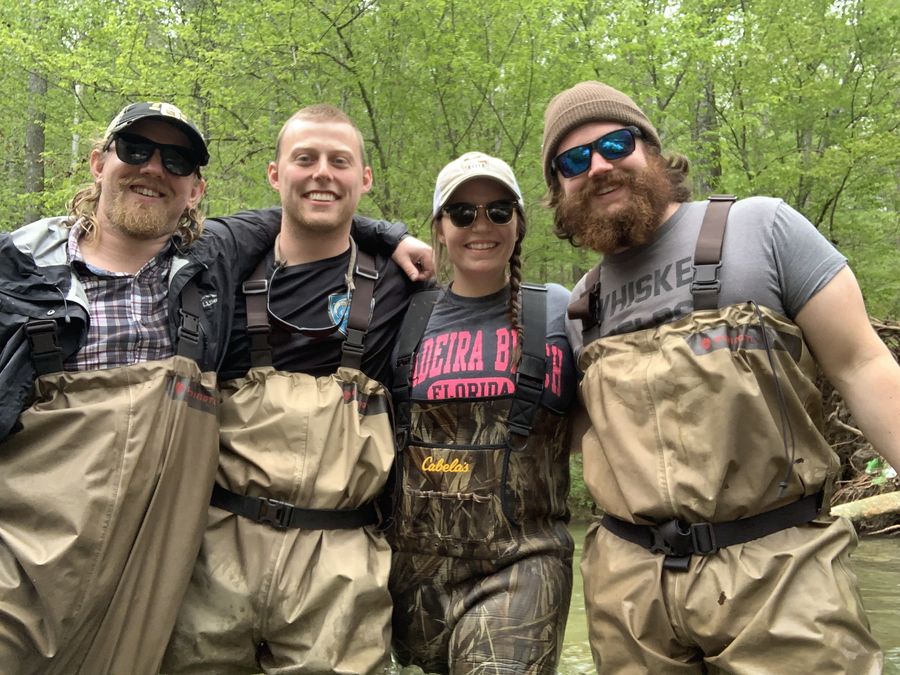 Four people in waders beside a stream