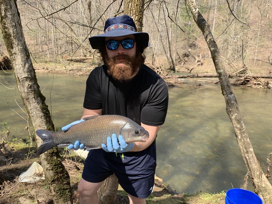 Holding a large sucker beside a stream