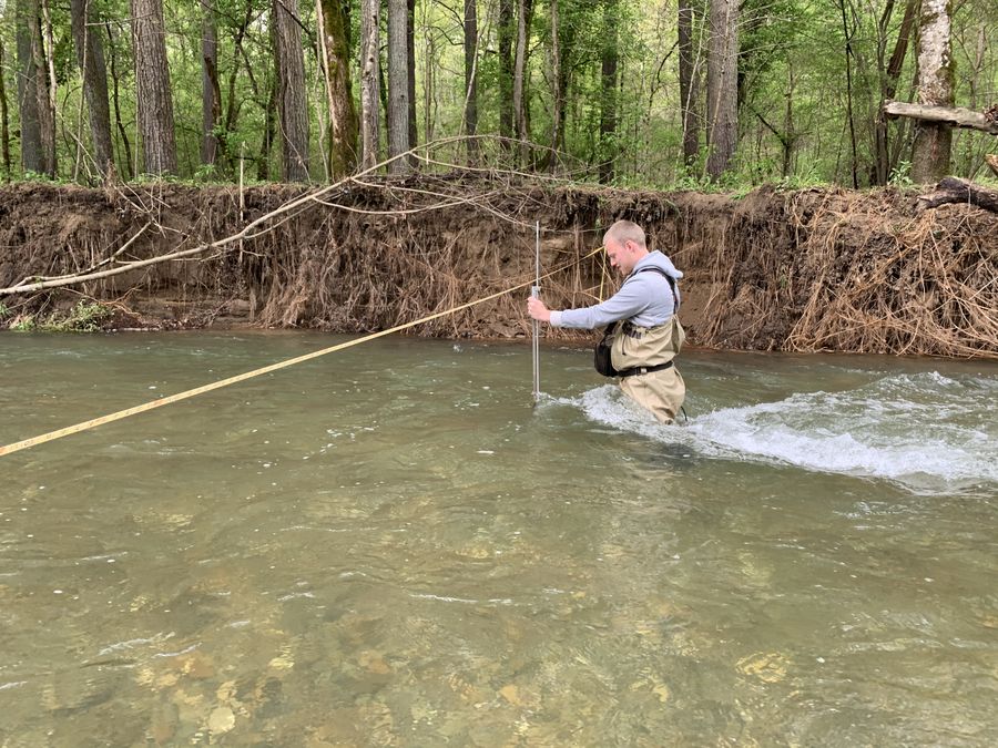 Wading across a stream with a measuring rod